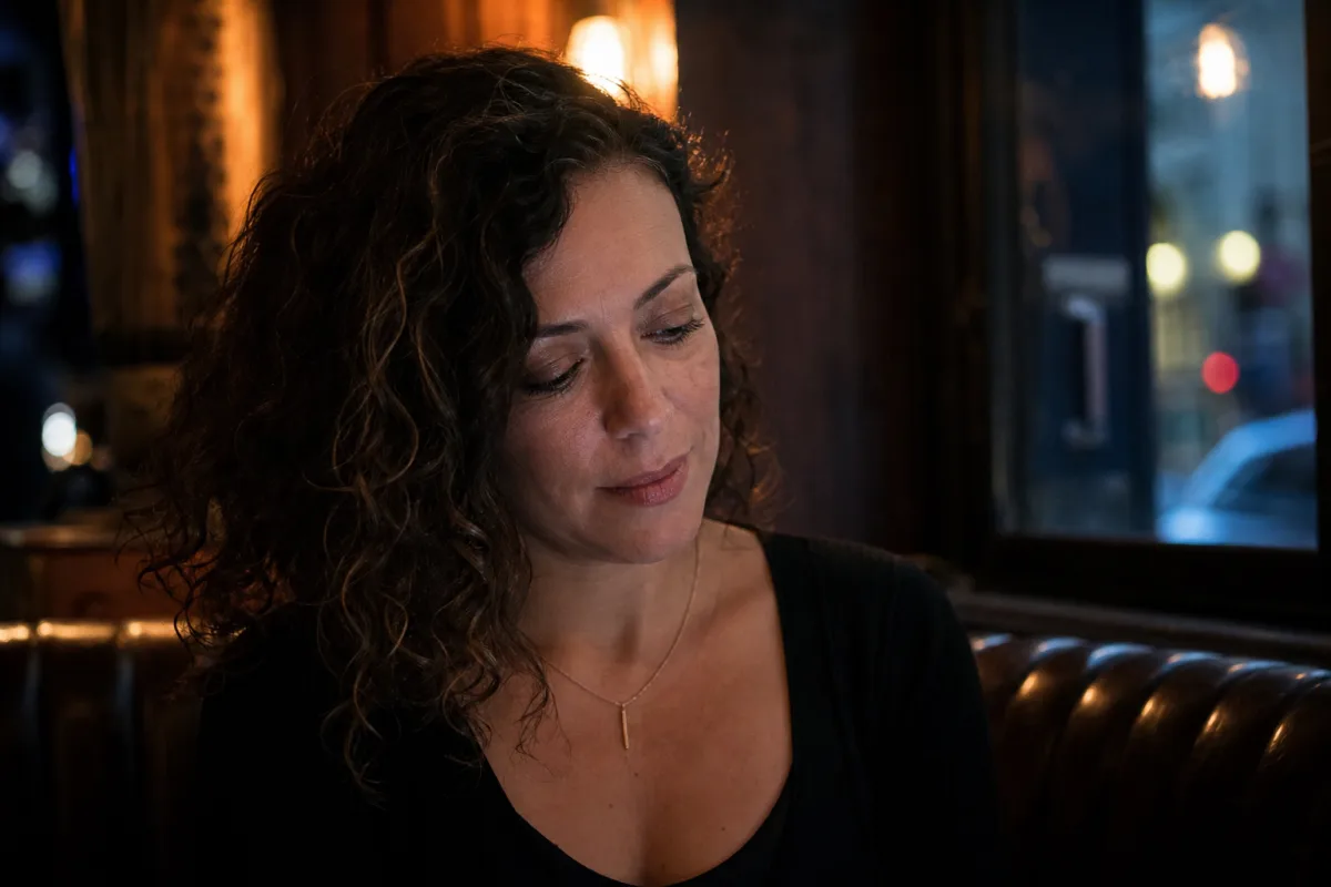 An independent adult woman in the ENM community sitting confidently alone in a bar